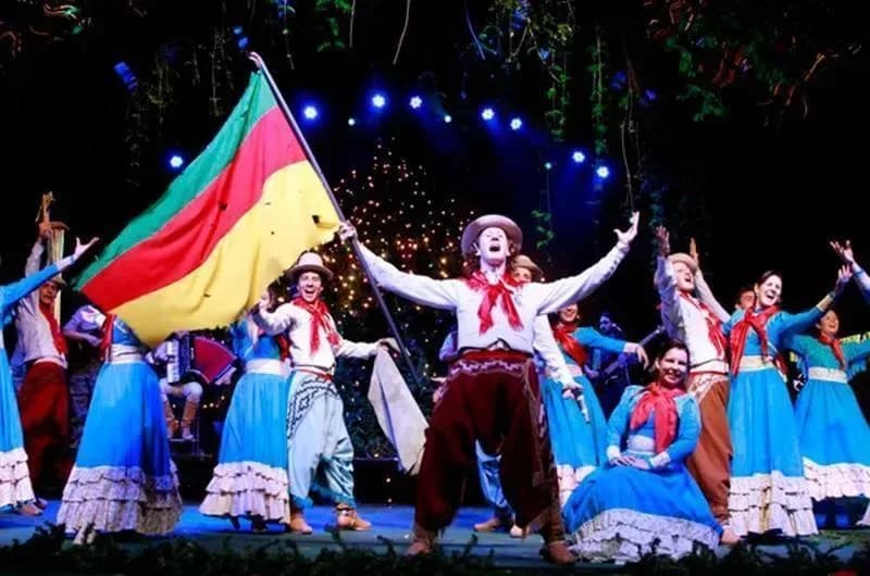 Noite Gaúcha na Churrascaria Garfo e Bombacha com dançarinos e uma grande bandeira no palco