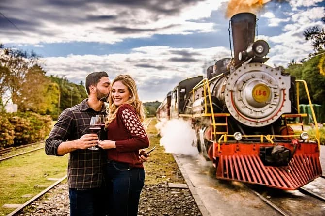 Tour Uva e Vinho com Maria Fumaça em Gramado, casal brinda diante da locomotiva